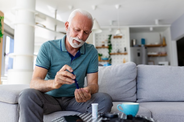 Photo mature man testing for high blood sugar man holding device for measuring blood sugar doing blood sugar test senioir man checking blood sugar level by glucometer and test stripe at home