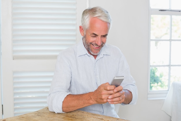 Photo mature man text messaging at home