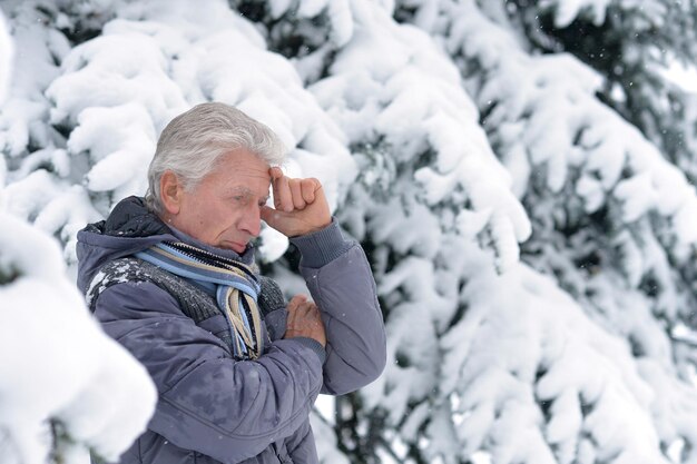 Mature man thinking about something, fir trees on background