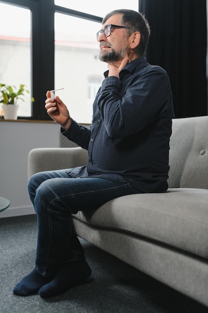 Mature man using an antiseptic throat spray at home