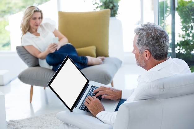 Mature man using laptop by woman