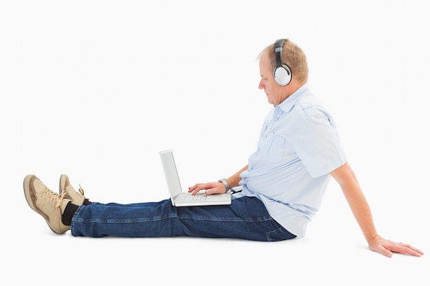 Зрелые человек, используя ноутбук, слушать музыку