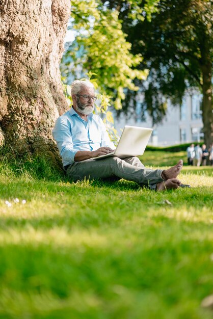 Зрелый мужчина с ноутбуком в парке