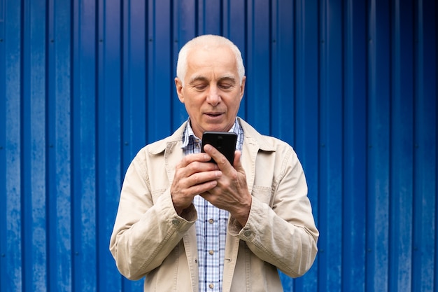 Photo mature man using smartphone in blue