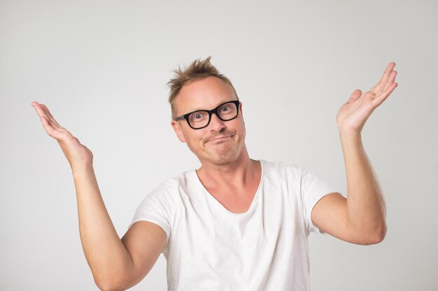 Mature man in white shirt shrugging shoulders who cares so what