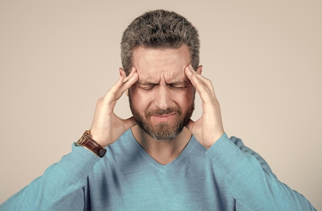 Mature man with beard suffer from headahce on grey background health