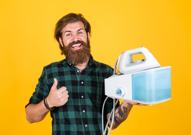 Mature man with beard and trendy hairstyle use steaming iron household