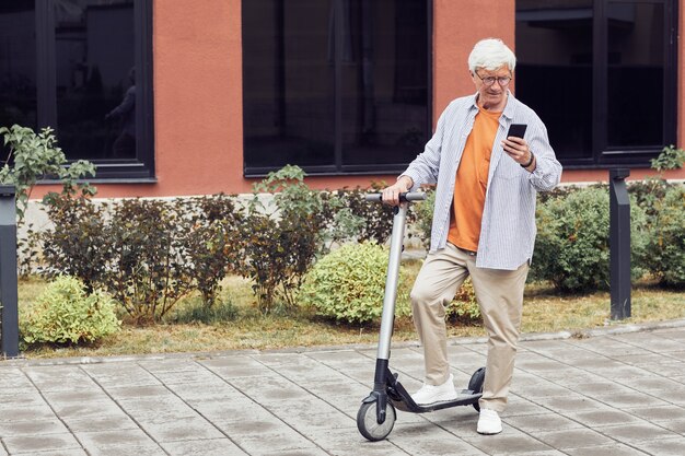 市内の電動スクーターを持つ成熟した男