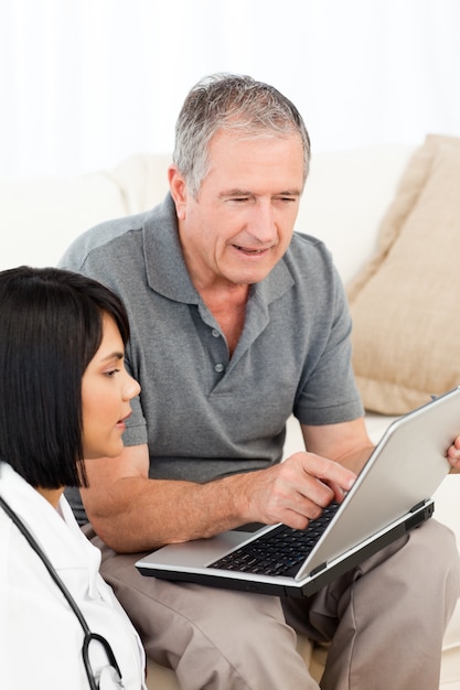 Mature man with his nurse looking at the laptop at home