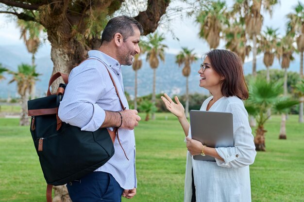 Mature man and woman business colleagues talking outdoors