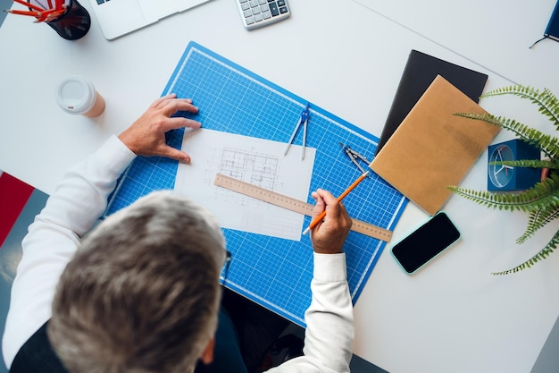 Mature man working on architectural project in office