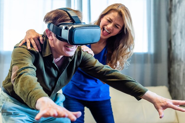 Mature married couple at home playing with virtual reality glasses. High quality photo