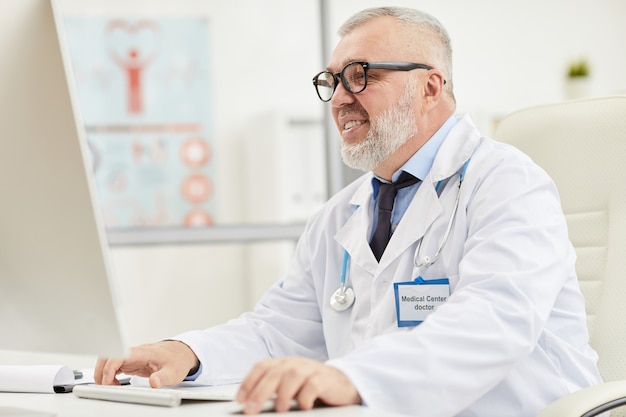 Mature medical specialist using computer at office