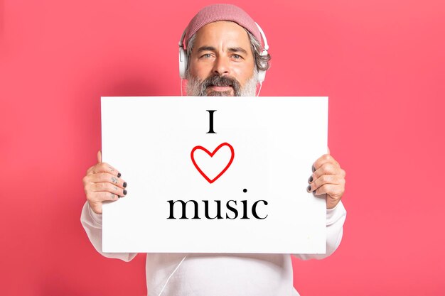 Mature modern man with headphones holding a sign with i love music text