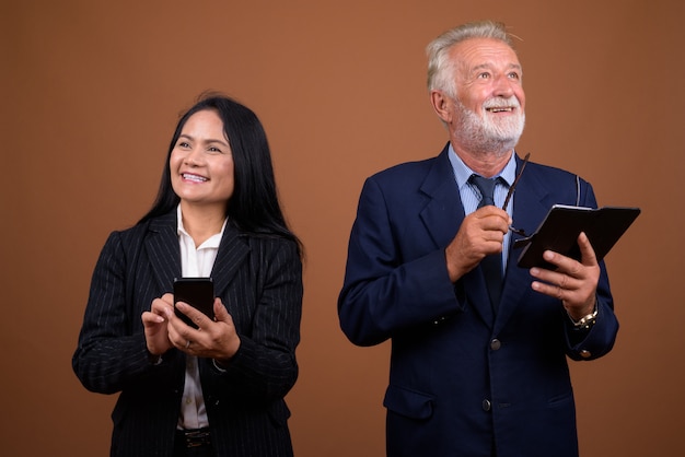 Mature multi-ethnic business couple on brown