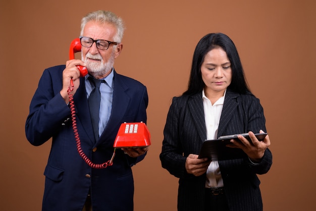 Mature multi-ethnic business couple on brown