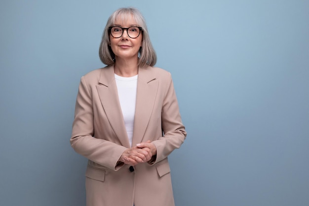 Mature old woman in a stylish jacket posing against a bright studio background