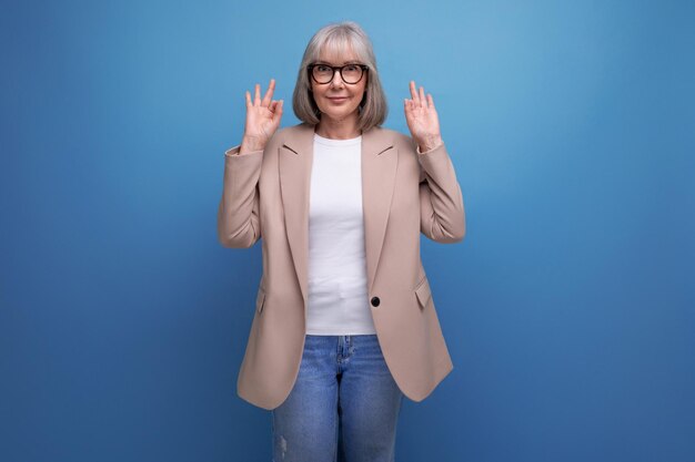 Mature old woman in a stylish jacket posing against a bright studio background