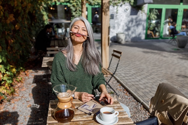 Mature pale hair stylish woman lifestyle portrait outdoors near cafe