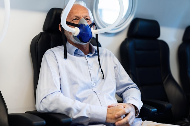 Фото Зрелый пациент дышит через кислородную маску во время терапии в барокамере в клинике