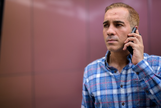 Mature Persian hipster man against glossy wall