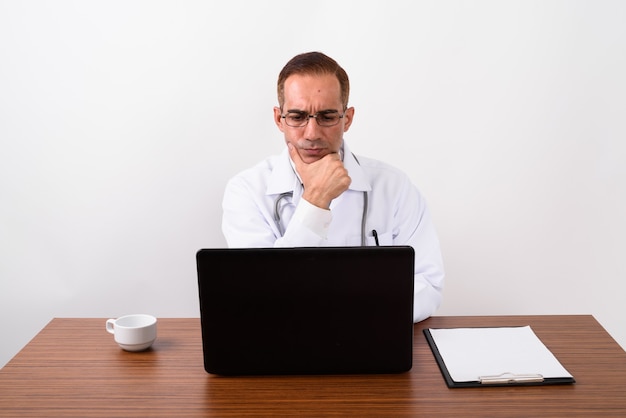 Mature Persian man doctor working behind desk