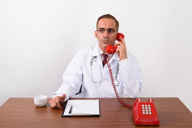 Mature Persian man doctor working behind desk