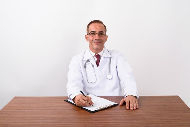 Mature Persian man doctor working behind desk