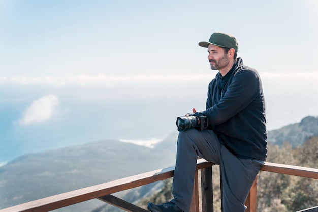 Mature person sitting at the viewpoint with camera happily enjoying looking at the horizon