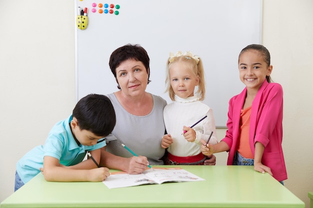 Mature preschool teacher and children in a classroom during class