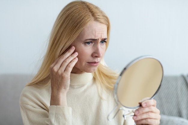 Mature Sad Woman Looking At Wrinkles In Mirror