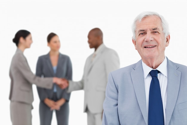 Mature salesman with trading partners behind him