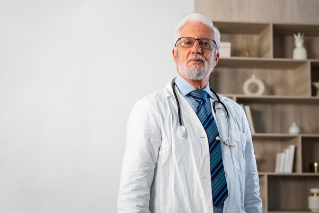 Mature senior male doctor in glasses medical uniform in hospital or doctor office general