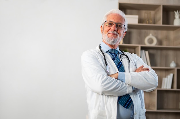 Foto dottore maschio anziano maturo con gli occhiali in uniforme medico sorridendo guardando la telecamera in ospedale o dottore