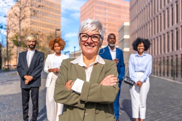 Photo mature smiling businesswoman standing proud next to colleagues