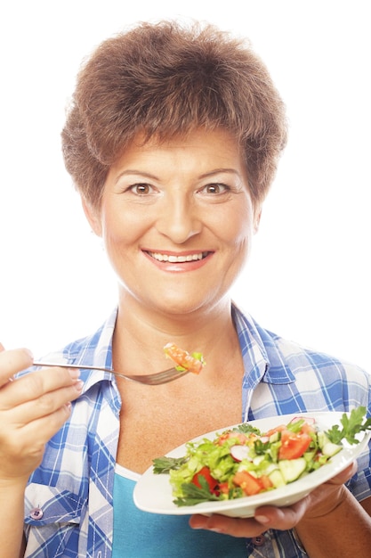 Foto donna sorridente matura che mangia insalata