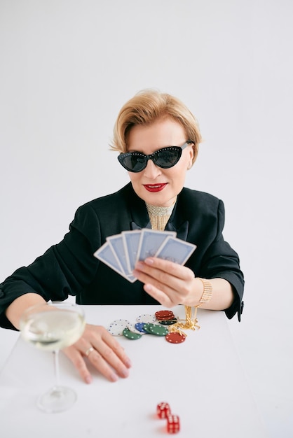 Mature stylish woman in black tuxedo and sunglasses in casino\
gambling fashion poker face hobby