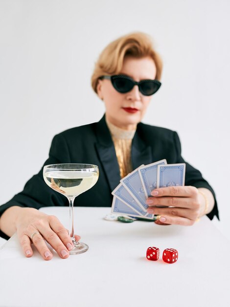 Mature stylish woman in black tuxedo and sunglasses in casino\
gambling fashion poker face hobby