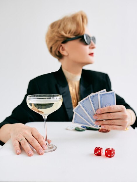 Mature stylish woman in black tuxedo and sunglasses in casino\
gambling fashion poker face hobby