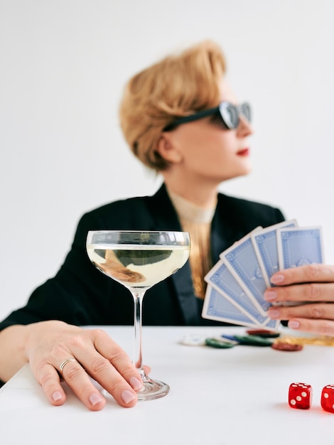 Mature stylish woman in black tuxedo and sunglasses in casino\
gambling fashion poker face hobby