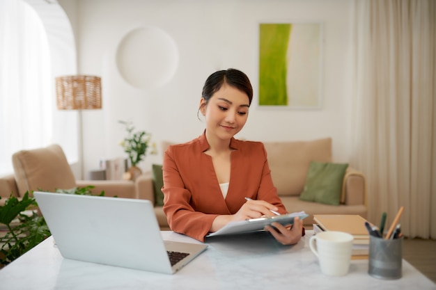 Mature successful business woman looking at mobile cell phone while at home in office work space