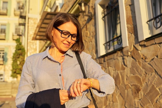 Mature successful business woman walking along city street