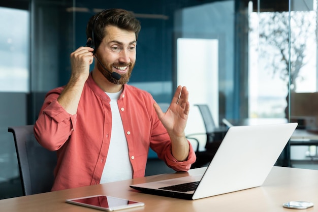 Uomo d'affari di successo maturo con cuffia per videochiamata che lavora all'interno dell'ufficio uomo che consulta online