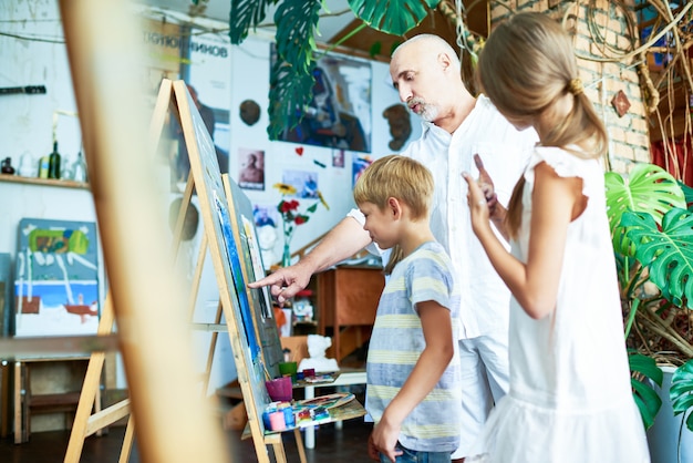 Mature Teacher Helping Kids in Art Studio