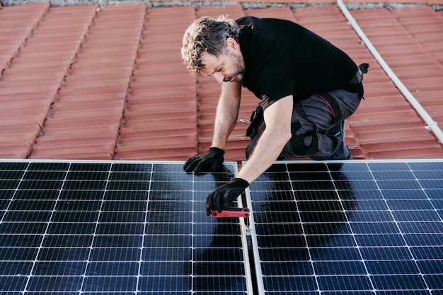 Photo mature technician man assembling solar panels on house roof for self consumption renewable energies