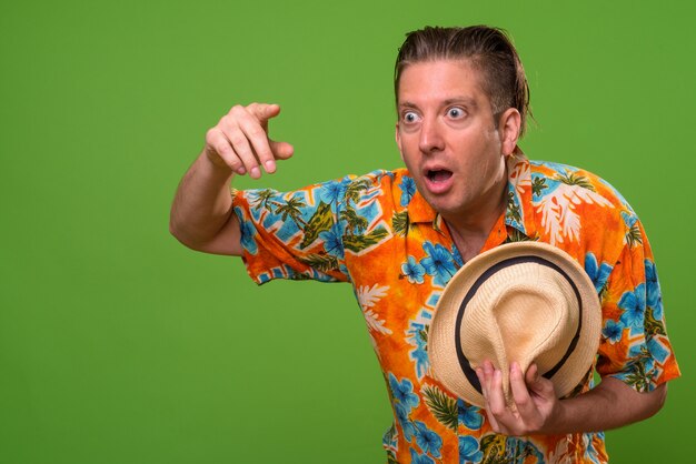 Mature tourist man ready for vacation against green background