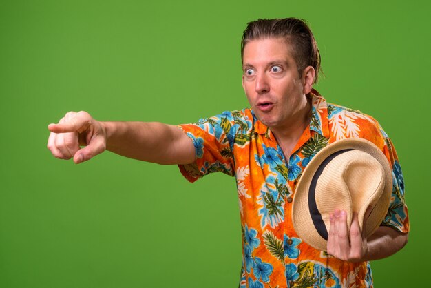 Mature tourist man ready for vacation against green background