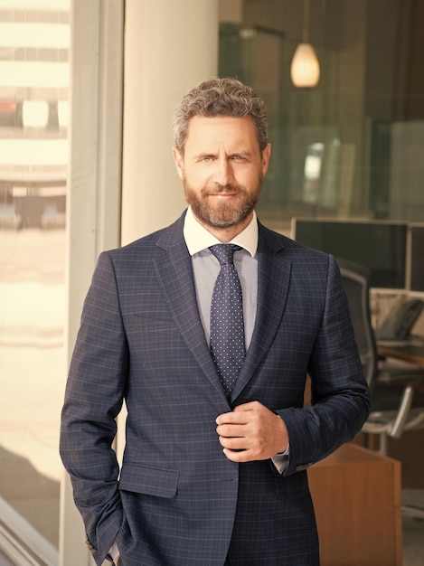 Mature unshaven man manager in businesslike suit outside the office business professional