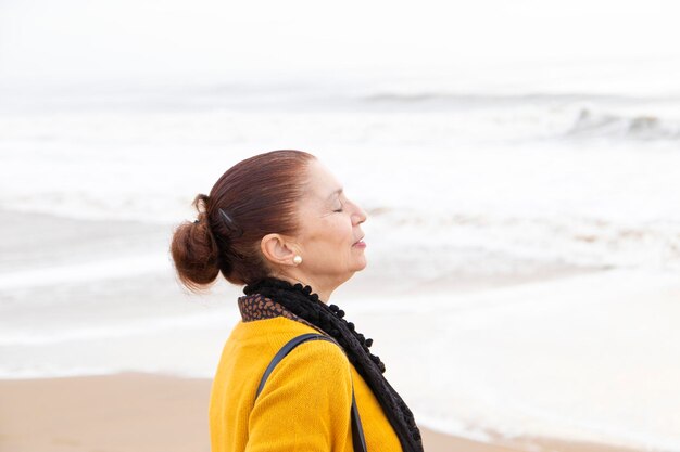 Mature woman breathing fresh sea air. Anxiety concept.