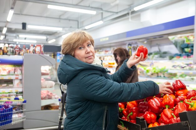 ファーマーズマーケットで野菜を買う成熟した女性